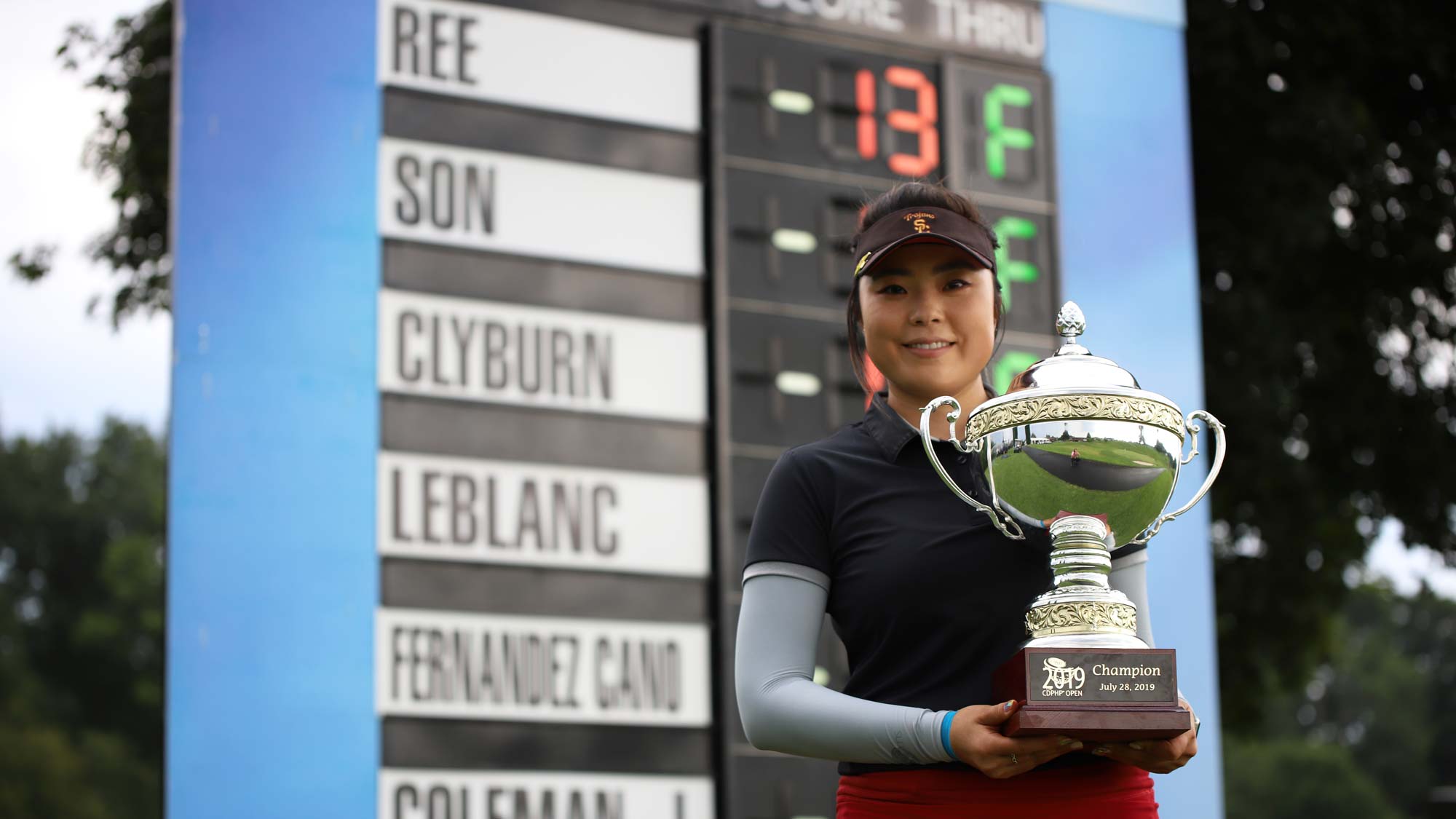 Robynn Ree with trophy by leaderboard